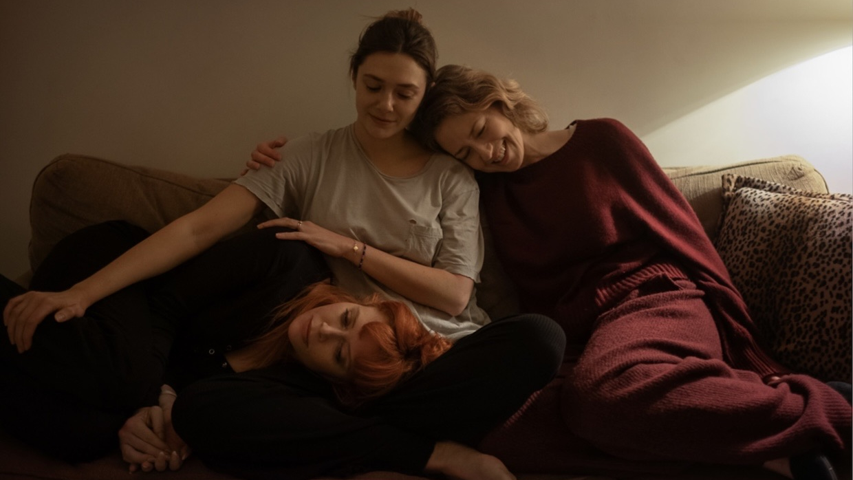 Three sisters cozy up to each other on a couch.